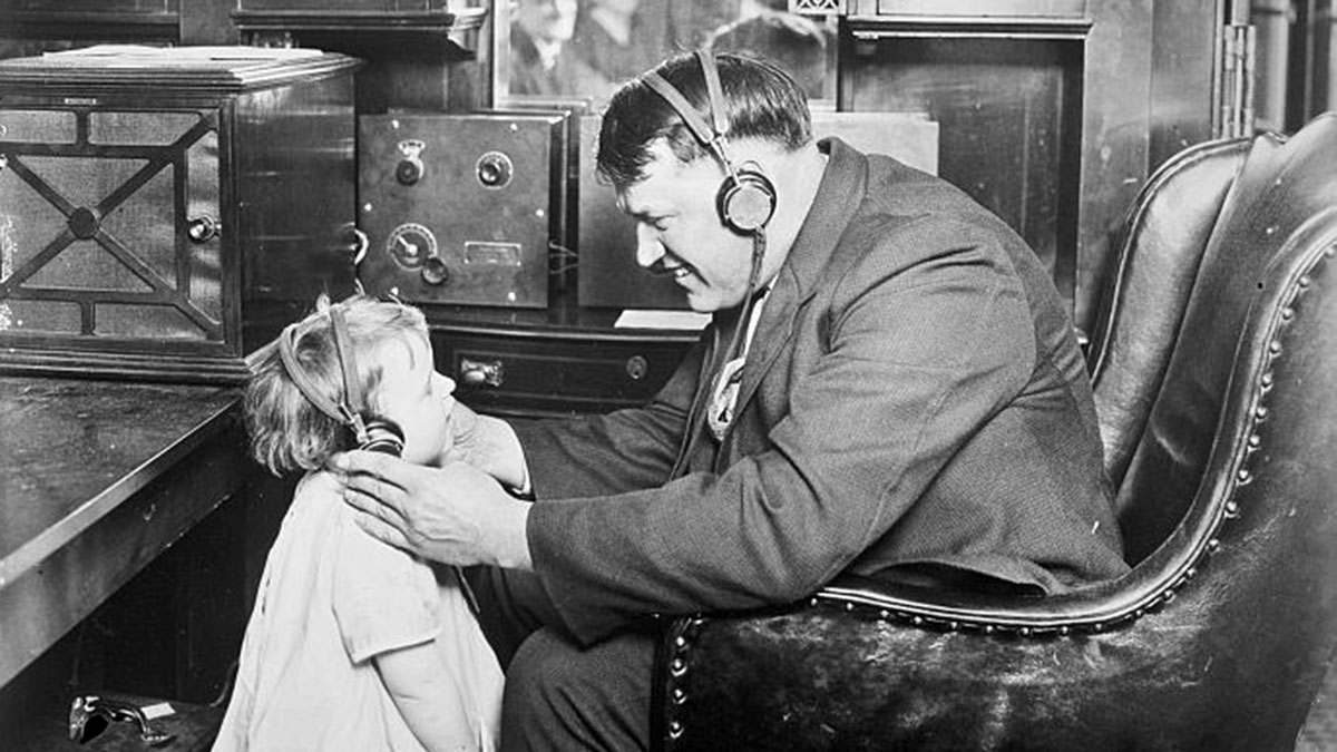 Dieses Bild erschien als Teil einer Anzeige/eines Artikels vom 25. April 1925 in St. Paul, Minnesota. Es illustriert den Plan der Great Northern Railway für den Radioempfang in ihrem transkontinentalen Zug „Oriental Limited“. Das Bild trägt die Bildunterschrift „Sogar die Kinder genießen das Konzert“. Der Oriental Limited war ein Personenzug, der zwischen Chicago, Illinois, und Seattle, Washington, verkehrte. Quelle: The Library of Congress, Wikimedia Commons